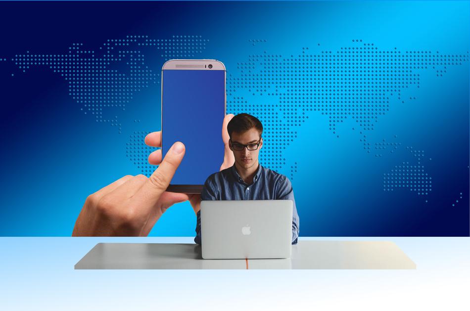 Entrepreneur, using laptop and smartphone in the hands, at blue background with the map