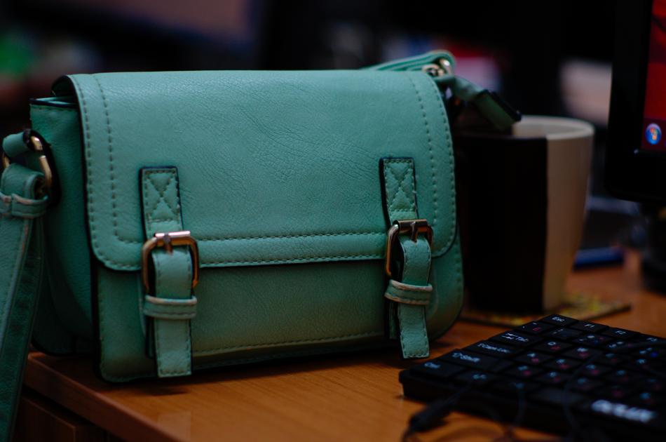 stylish green womenâs Bag on desk in Office