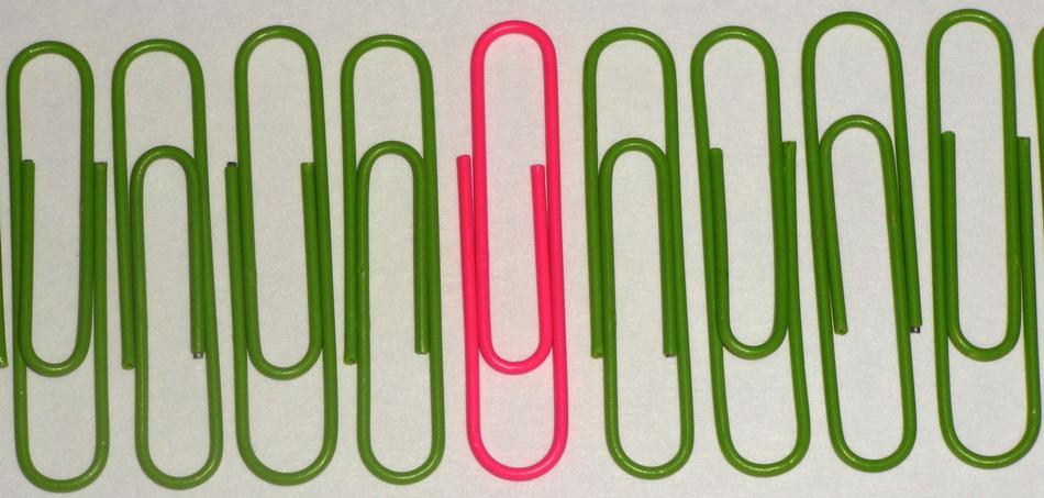 Pink paperclip among the green paperclips