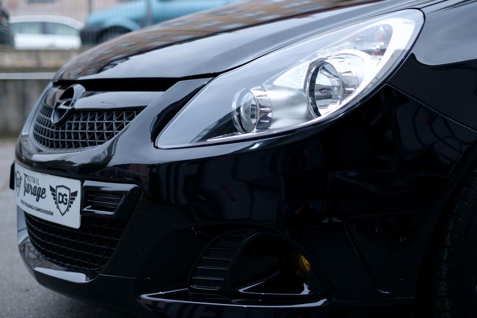 Side view of the shiny, black 'Opel' car, with the headlights, outdoors