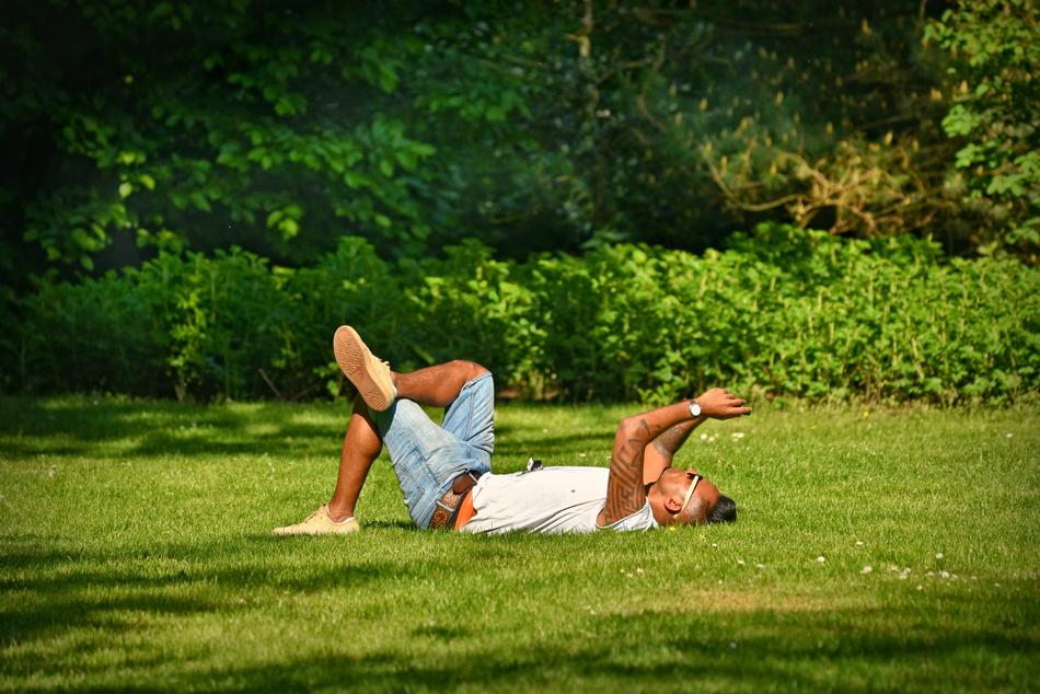 man lies on green grass in the park