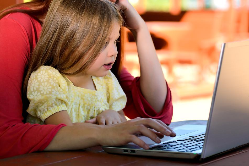 Mother with the child, using laptop, on the table