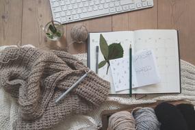 a notebook with a pencil lies near the yarn