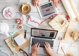 man works behind laptop at work desk with documents