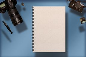 Digital Camera and accessories near blank Notebook