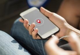 Person, holding charging smartphone with geolocation sign on the screen