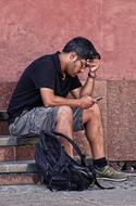 Man with Mobile Phone Sitting on step at wall