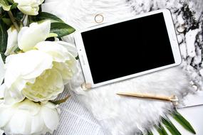 a bouquet of white peonies, a golden pen and a tablet