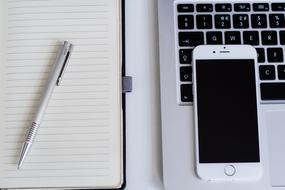 pen on notebook and smartphone on laptop on the table