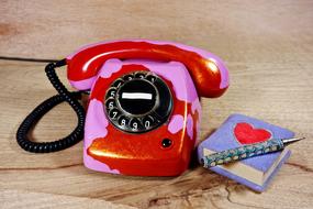 photo of a red-pink retro phone and a notebook with a pen