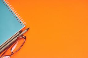corner of blue notebook on orange Color Background
