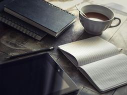 tablet, notebook and cup with coffee on the table