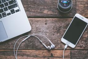 iPhone with headphones, laptop and lens on the table