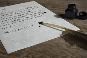 Beautiful bird feather with the ink, on the paper, near the bottle