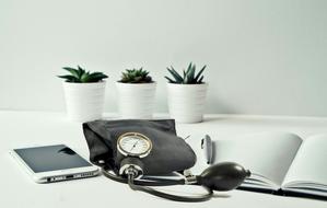 an open notebook, a smartphone and a device for measuring pressure on the table