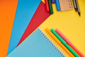 colored paper, colored markers and a notebook on the table
