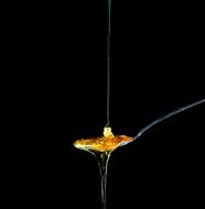 trickle of honey in a spoon on a black background