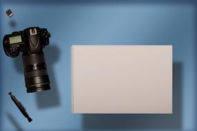 Beautiful, black camera, tools and white notebook, at blue background