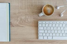 coffee in cup, keyboard and notebook on desktop