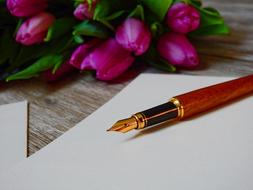 fountain pen on a white sheet and a bouquet of tulips