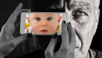 photo of baby boy on Smartphone in female hands at Face of old Man