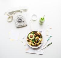 Colorful and beautiful diet dish in the bowl, cutlery and drink, near the white telephone