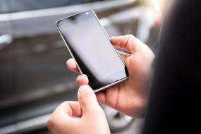 smartphone in the hands of a girl on the background of the car