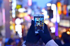 smartphone in female hands at city lights