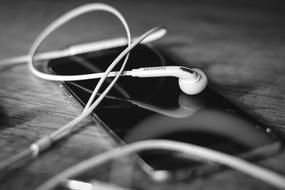 Black and white photo, with the close-up of the headphones and shiny smartphone