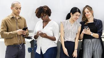 People, using devices and accessories, near the white wall