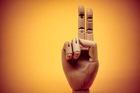 wooden hand gesture on yellow background