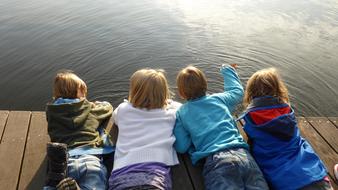children lie on a wooden pier