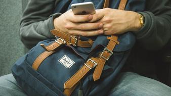iPhone in hands on a backpack close-up