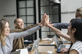 Achievement of Agreement, four young people making high five hand gesture in office