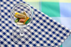 multicolored capsules in a transparent glass on the table
