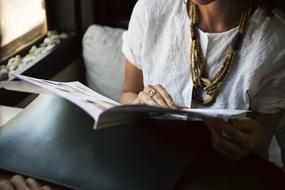 Woman with ring, reading magazine, while sitting in the restaurant