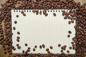 coffee beans around a notebook with clean sheets