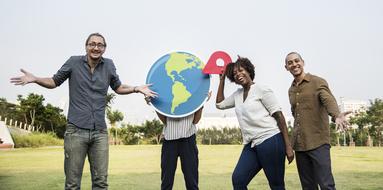 Smiling people, with the colorful Earth globe and red geolocation sign, among the plants