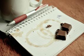 coffee cup and chocolates on open notebook