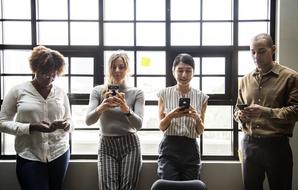 various race people with smartphones in office