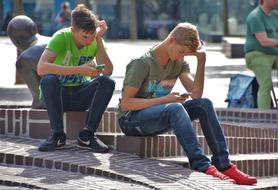 students are playing on phone on a street