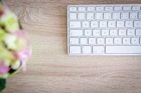 white keyboard and flowers on wooden desk