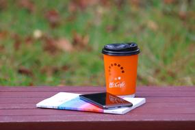 book, smartphone and coffee on a wooden bench