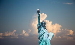 Green Statue of Liberty in New York City Harbor, at colorful and beautiful sky with the clouds