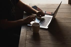 female hands at laptop on wooden table