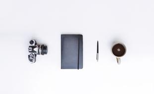 photo camera, diary, pen and a cup of coffee on a white background