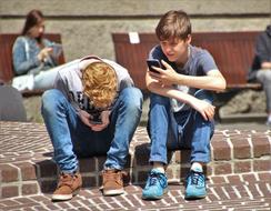 two students play pokemon go on a city street