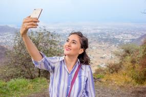 Portrait of the smiling woman, taking a selfie, among the beautiful and colorful nature