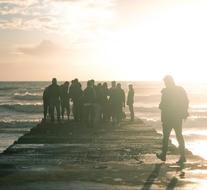 Group of people near end of pier at sunset