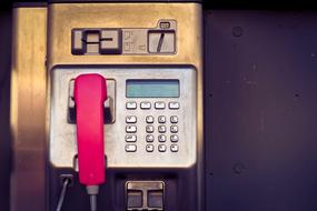 Macro photo of old payphone with a red handset